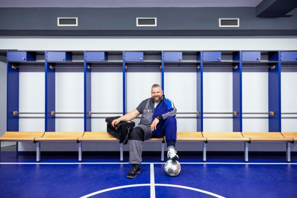 Mann sitzt in Spielerkabine im Fußballstadion auf einer Bank