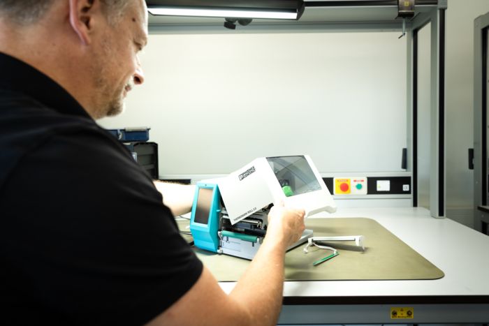 Technical support employee sticking an inspection sticker on a serviced printer