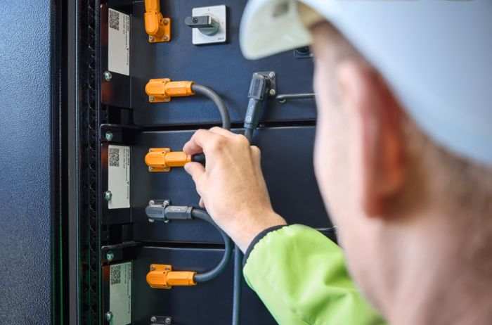 An employee working on the battery-pole connectors in the battery storage system in front of the All&nbsp;Electric&nbsp;Society&nbsp;Factory in Blomberg, Germany
