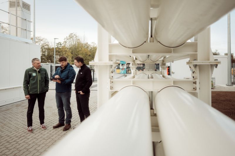 People looking at a smart device next to a hydrogen tank