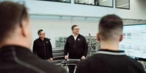 Employees in front of a monitor in the production hall for the morning shop floor management session