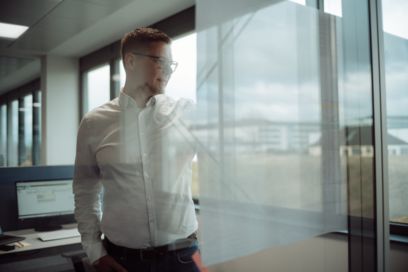 Person im Business-Outfit schreibt an die Glaswand