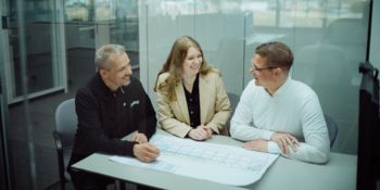 Drei Personen aus den Bereichen Gebäudeplanung, Elektroinstallation und Gebäudebetrieb sitzen zusammen und besprechen ihre Arbeit