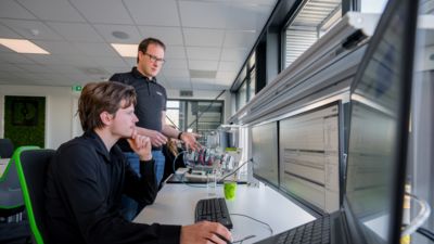 Twee mensen aan een bureau voor een scherm