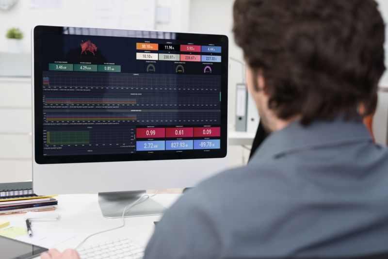 Engenheiro a olhar para um monitor a observar gráficos de monitorização de dados