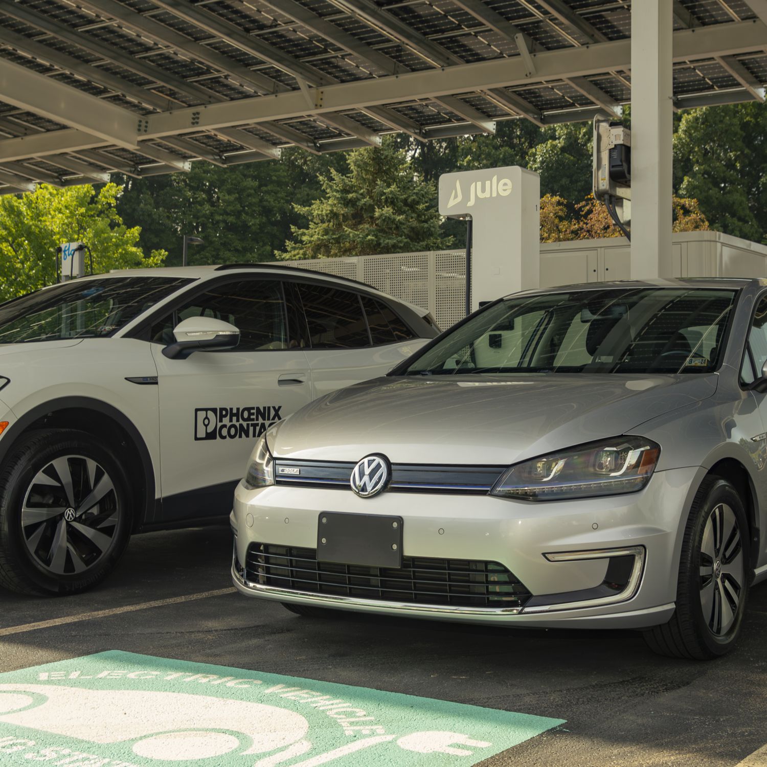 A photo of two electric cars parked in an electric vehicle solar port