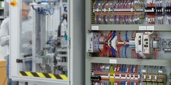 Electrical designer stands at a machine with a control cabinet