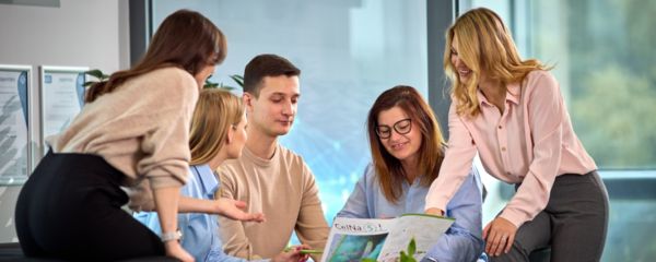 Pracownicy siedzą razem i przeglądają firmową gazetę