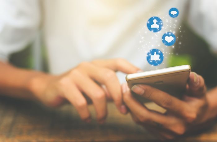 Smartphone mit Social Media-Icons in einer Hand