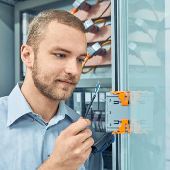 Persona di fronte allo sportello aperto del quadro elettrico che collega la bobina di Rogowski direttamente al dispositivo per la misurazione dell'energia EMpro