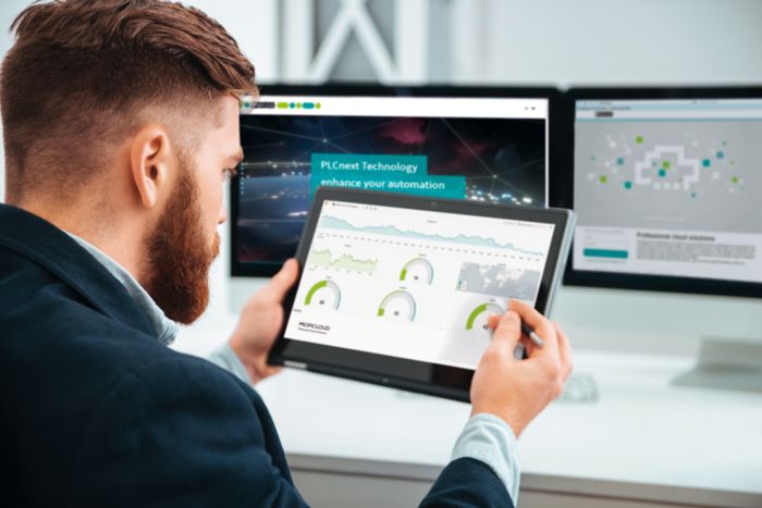 Man with tablet in front of monitors while checking system availability