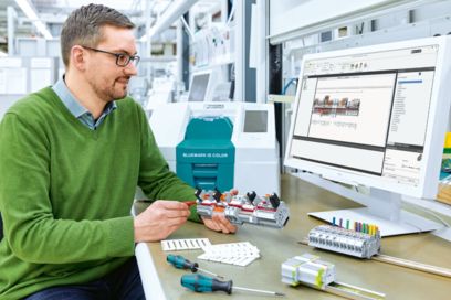 Person prüft eine bestückte Klemmenleiste mit Hilfe der Planungssoftware PROJECT complete