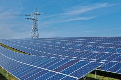 Installation solaire au sol dans un ciel bleu avec un pylône électrique en arrière-plan
