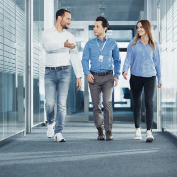 Drei Mitarbeitende gehen gemeinsam über den Flur