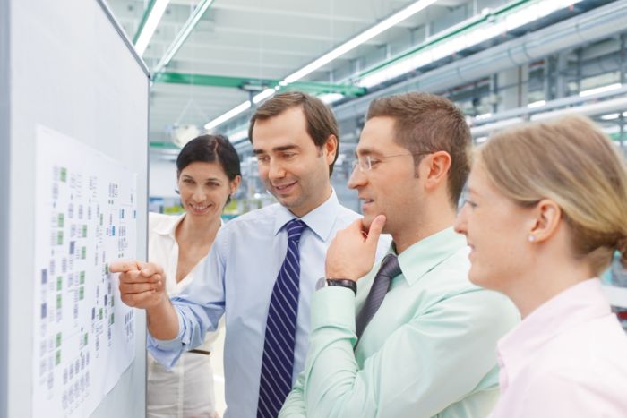 Group of people standing in front of a board in discussion