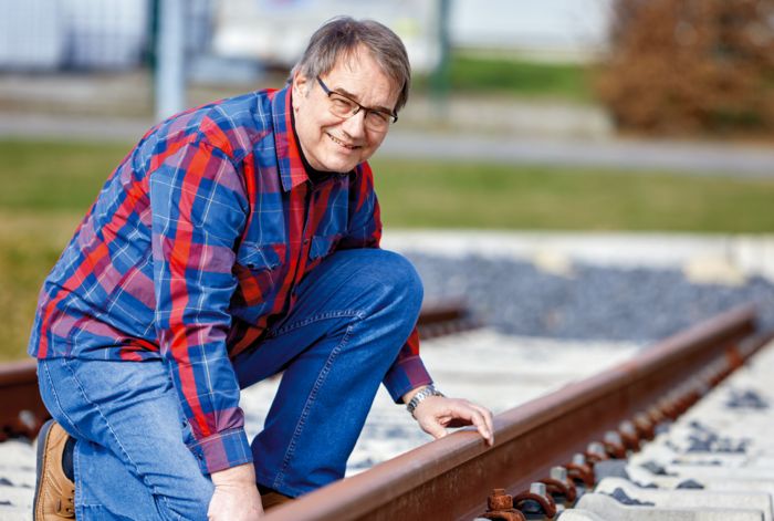 Rudolf Mühlenbein from Voestalpine Signaling kneeling in front of a railway line