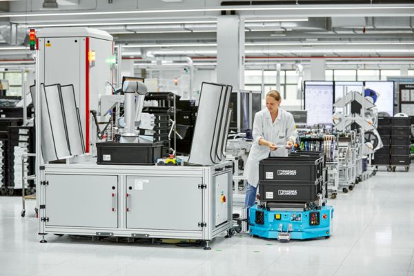Two automated guided vehicle systems in front of a production environment with people