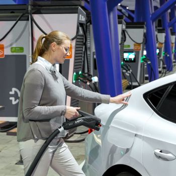 Person charging an electric car at a fast charging station with an HPC charging cable