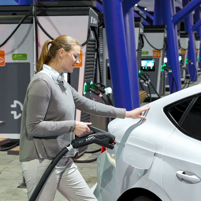 Person charging an electric car at a fast charging station with an HPC charging cable