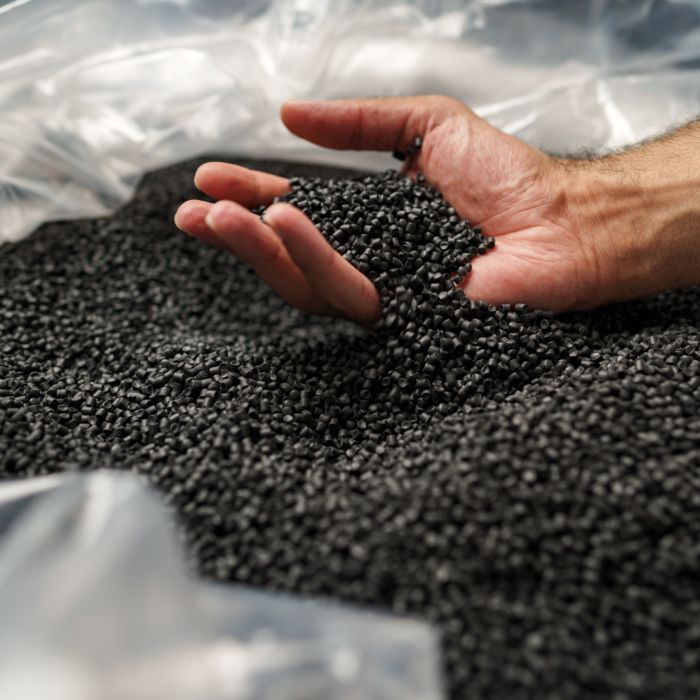 O mână introdusă într-o pungă plină de granule negre