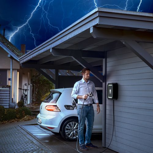 Electric car and home charger in the carport during a thunderstorm