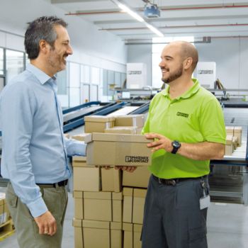 Ein Man übergibt ein Paket an einen Mitarbeiter von Phoenix Contact.