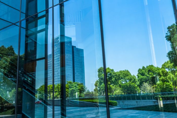 Uitzicht door een ruit op een gebouw omringd door bomen
