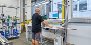 Un collaborateur découpe des rails DIN sur un poste de travail assisté par logiciel
