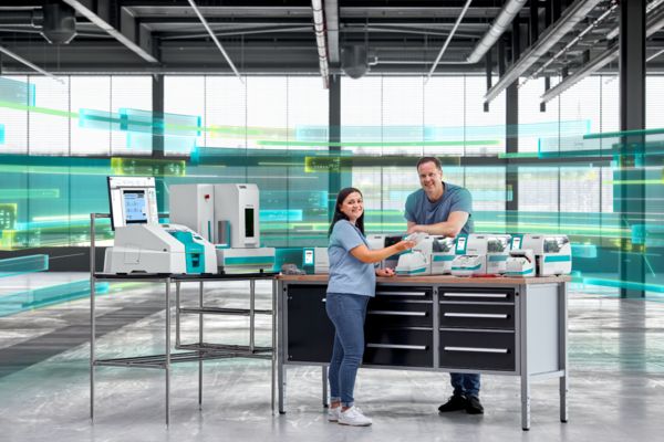 Zwei Mitarbeitende stehen in einer Markierungszelle in einer großen Fertigungshalle