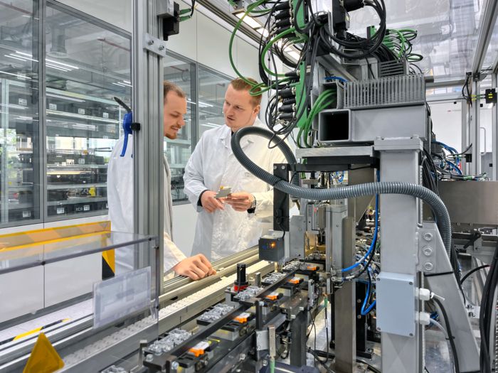 Сотрудники на производстве PLC-INTERFACE с видом с производственной линии