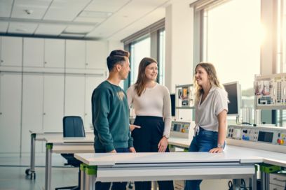 Junge Mitarbeitende stehen zusammen und unterhalten sich