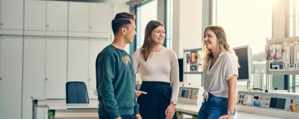 Junge Mitarbeitende stehen zusammen und unterhalten sich