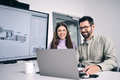 Mitarbeitende arbeiten zusammen an einem Laptop