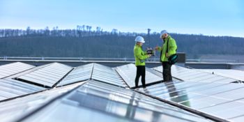 Electrician in a PV rooftop system talking to a Phoenix Contact employee who is holding a surge protective device