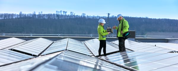 Angajați stând pe acoperiș în mijlocul unei instalații solare