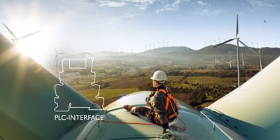 Técnicos de assistência em um aerogerador com logotipo PLC-INTERFACE