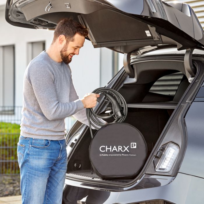 Person retrieves CHARX connect eco AC charging cable from the trunk of an electric car