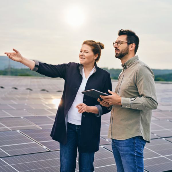 Mitarbeitende stehe auf einem Dach mit Solarpanels und schauen in die Ferne