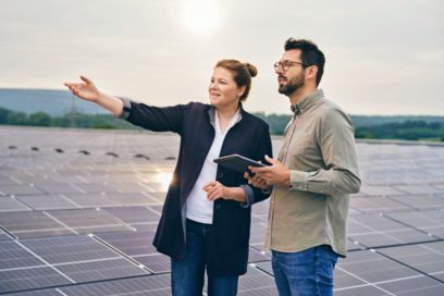 Mitarbeitende stehe auf einem Dach mit Solarpaneels und schauen in die Ferne