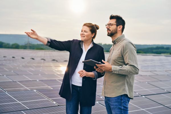 Mitarbeitende stehen auf einem Dach mit Solarpanels und schauen in die Ferne