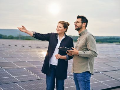 Mitarbeitende stehe auf einem Dach mit Solarpaneels und schauen in die Ferne