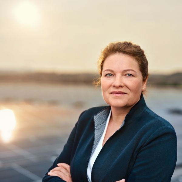 Eine Mitarbeiterin steht vor Solarzellen auf einem Dach