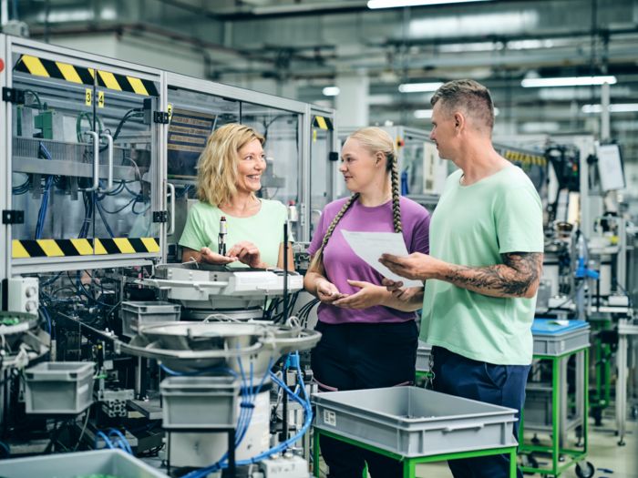 Drei Mitarbeitende stehen in der Produktion