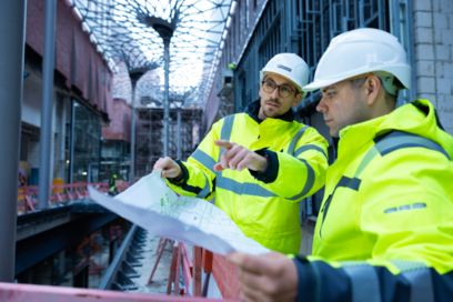 Deux personnes avec des vêtements de protection et un plan de construction