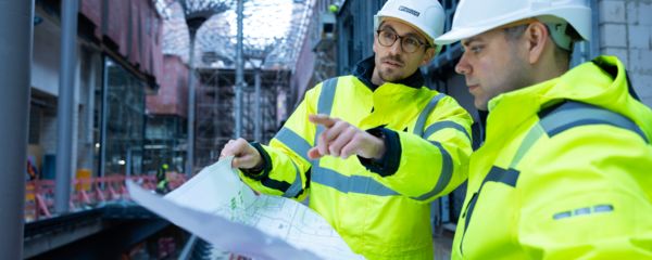 Deux personnes avec des vêtements de protection et un plan de construction