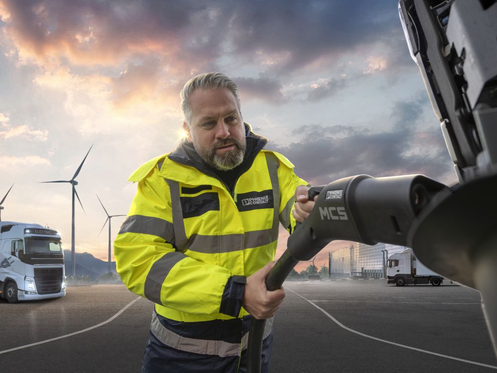 Une personne charge un camion électrique avec un connecteur de charge MCS
