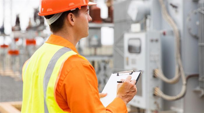 Man with clipboard and construction hat taking notes