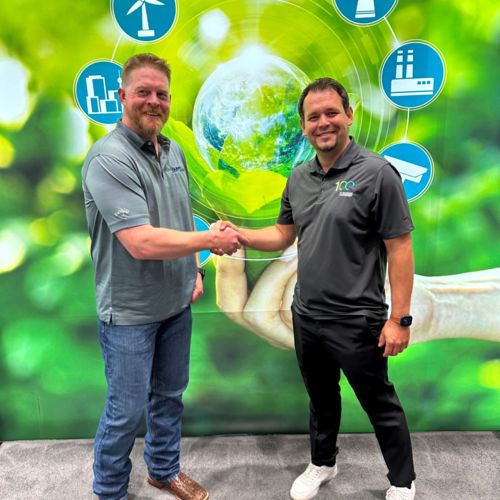 Two men shake hands in front of a wall with an abstract mural featuring a green nature motif with various green energy logos