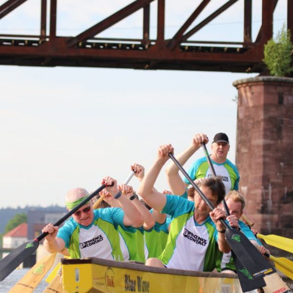 Mitarbeitende paddeln als Team in einem Ruderboot