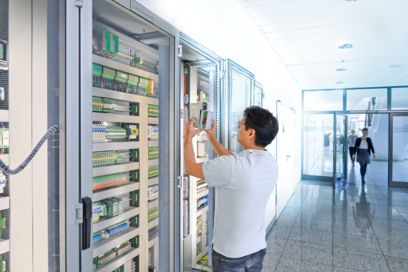 Man at a control cabinet containing connection technology for building control